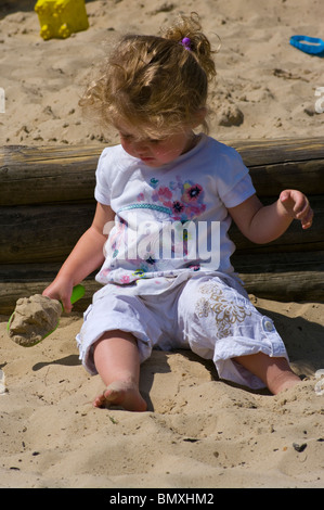 2 ans, fille, jouant dans un bac à sable avec une pelle en plastique Banque D'Images