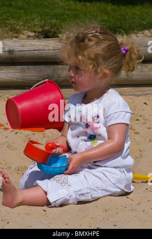 2 ans, fille, jouant dans un bac à sable avec des jouets en plastique Banque D'Images