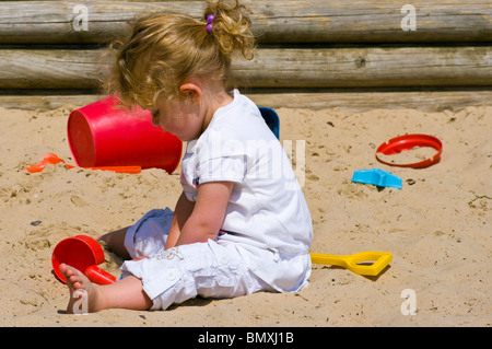 2 ans, fille, jouant dans un bac à sable avec des jouets en plastique Banque D'Images