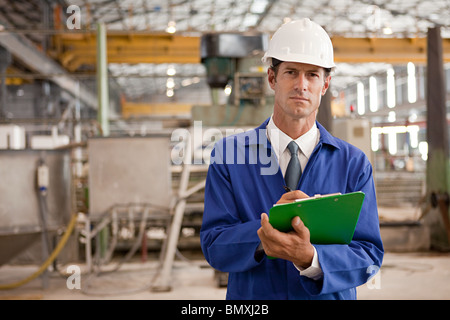 Homme mature avec presse-papiers en usine Banque D'Images