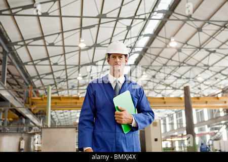 Homme mature avec presse-papiers en usine Banque D'Images