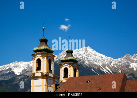 Les clochers et les toits de la basilique de Wilten à Innsbruck, les pics de Karwendel et ciel bleu avec petit nuage moelleux Banque D'Images