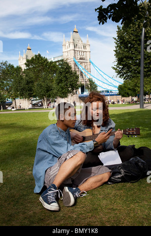 Deux amis leur pratique de la musique ensemble dans les champs de potiers, un espace vert et une partie de plus de Londres près de Tower Bridge. Banque D'Images