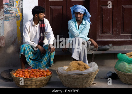 Deux hommes chat tout en vendant les tomates et les nouilles dans la rue à Durbar Square, Katmandou, Népal. Banque D'Images