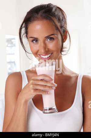 WOMAN DRINKING milk-shake AUX FRAISES SMOOTHIE OU Banque D'Images