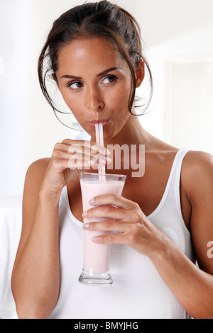 WOMAN DRINKING milk-shake AUX FRAISES SMOOTHIE OU Banque D'Images