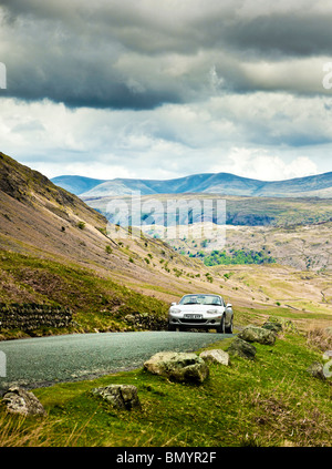 La conduite, UK, conduite de voiture de sport sur une route de montagne dans la région du Lake District, d'un voyage dans la région de Cumbria, Angleterre, Royaume-Uni Banque D'Images