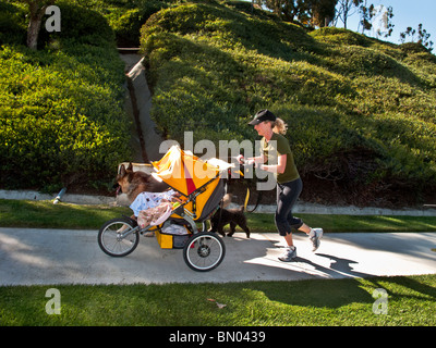 La santé de la jeune mère de jumeaux se heurte à une colline escarpée dans Laguna Niguel, California, poussant leur poussette et accompagnée de son Banque D'Images