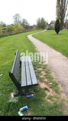 Banc de parc avec des canettes de bière vides jonchés autour d'elle. Banque D'Images