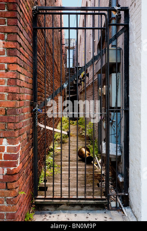 Portail en fer forgé noir verrouillé fixe allée entre les bâtiments en brique à Ybor City area de Tampa, en Floride Banque D'Images