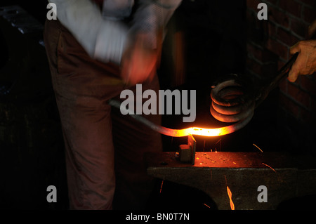 Blacksmith hammering white fer chaud sur une hardy sur une enclume Banque D'Images