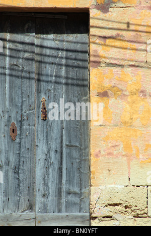 Une vieille porte en chêne patiné et décolorées avec rusty les verrous posés dans un mur en pierre jaune, Dingli, Malte Banque D'Images