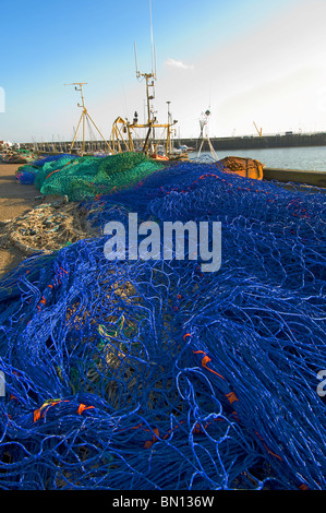 Les filets de pêche au chalut allongé sur le quai à un port de pêche Banque D'Images