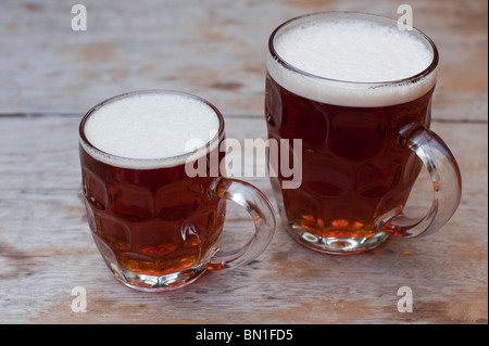 Demi-pinte et une pinte de bière 'vieux' école buissonnière sur une table d'extérieur dans un pub. Banque D'Images