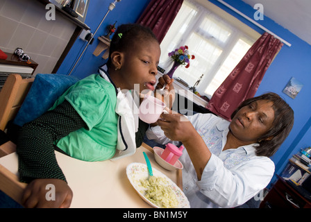 Aider la mère de sa fille handicapée de 10 ans (Syndrome de Pallister-Killian-PKS) avec l'alimentation, Londres, Royaume-Uni. Banque D'Images