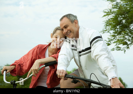 Mature couple riding bikes, appuyé contre l'un l'autre Banque D'Images