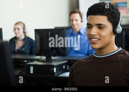Student listening to headphones in computer lab Banque D'Images