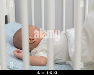 Six semaine mignon bébé garçon couché dans un lit de bébé Banque D'Images