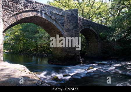 Une rivière coule sous un vieux pont voûté en pierre Banque D'Images