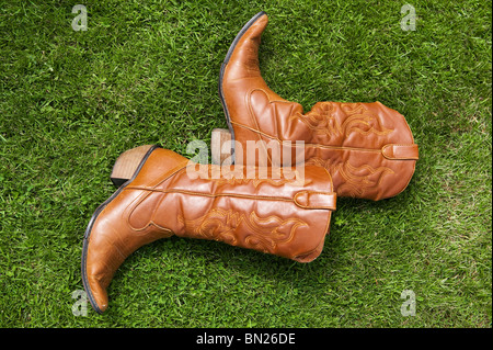 Une paire de bottes de cowboy en cuir Havane pour femmes, couchée sur l'herbe, Royaume-Uni Banque D'Images