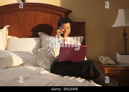 Chinese businessman using laptop in hotel room Banque D'Images