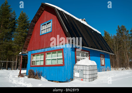 Chalet en bois dans les bois en hiver. Blue House dans une forêt de conifères. La Carélie, Russie. Banque D'Images