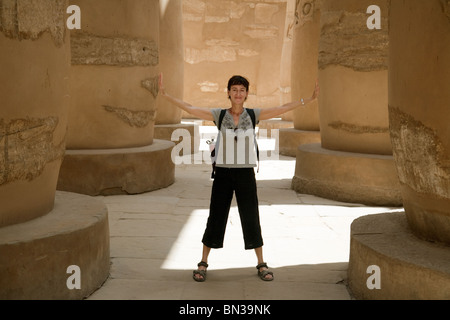 Un touriste dans la salle hypostyle 'holding up les colonnes', Temple de Karnak, Louxor, Egypte Banque D'Images