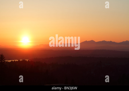 Coucher du soleil voilé de Bellevue Washington à la recherche sur les montagnes olympiques avec une lanière de Puget Sound dans l'espace moyen gauche. Banque D'Images