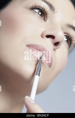 Young woman applying lipgloss Banque D'Images