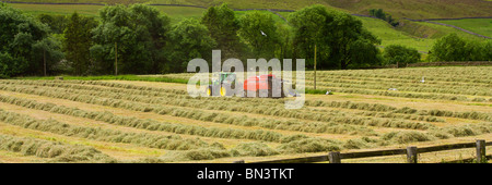 Le tracteur dans le champ de travail de la réalisation de balles de foin / herbe coupée Banque D'Images