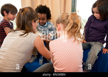 Enseignant de maternelle l'application d'un plâtre sur jambe garçons Banque D'Images