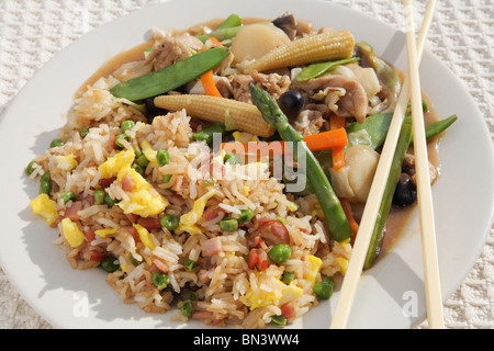 Assiette en gros plan de poulet chinois coloré et de repas sauté aux légumes avec baguettes Banque D'Images