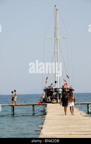 Les vacanciers qui arrivent sur la plage de Camel Bodrum Turquie SW à partir de leurs bateaux à voile goélette en bois Banque D'Images