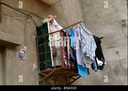 Vieille Femme wadhing vêtements sur son balcon en face de la mosquée Ibn Tulun Caire Egypte Banque D'Images