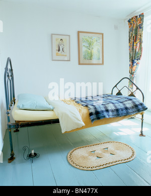 Seule la fonte lit avec jet blue vérifié en blanc chambre avec petit tapis sur le parquet en bois peint bleu pastel Banque D'Images