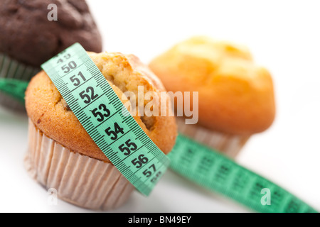 Muffins avec mètre ruban sur fond blanc Banque D'Images