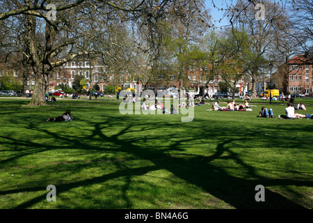 Sunseekers profitant soleil du printemps sur Parsons Green, Fulham, London, UK Banque D'Images