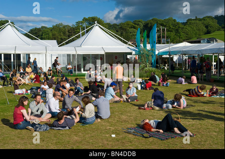 Les gens se détendre assis sur l'herbe en début de soirée au soleil Hay Festival 2010 Hay-on-Wye Powys Pays de Galles UK Banque D'Images