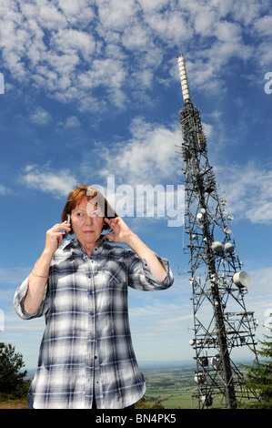 Femme à l'aide d'un téléphone mobile à côté de la station de transmission Le Wrekin qui est une station de radiodiffusion et télécommunications Banque D'Images