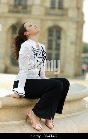 Jolie femme relawing affaires assis sur le bord de la fontaine en pierre à Bordeaux, France Banque D'Images