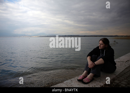 Femme regardant le ciel orageux sur le lac de Garde, Italie Banque D'Images