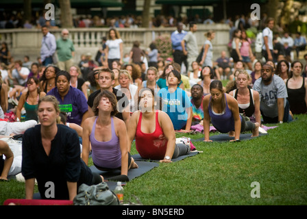 Des centaines de pratiquants de yoga de tous les niveaux participent à une classe de yoga donnés dans Bryant Park à New York Banque D'Images