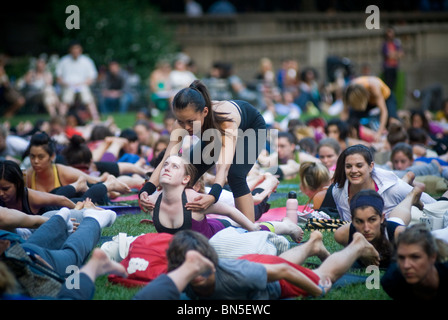 Des centaines de pratiquants de yoga de tous les niveaux participent à une classe de yoga donnés dans Bryant Park à New York Banque D'Images