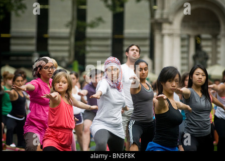 Des centaines de pratiquants de yoga de tous les niveaux participent à une classe de yoga donnés dans Bryant Park à New York Banque D'Images