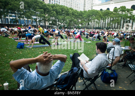 Des centaines de pratiquants de yoga de tous les niveaux participent à une classe de yoga donnés dans Bryant Park à New York Banque D'Images