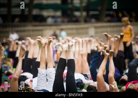 Des centaines de pratiquants de yoga de tous les niveaux participent à une classe de yoga donnés dans Bryant Park à New York Banque D'Images