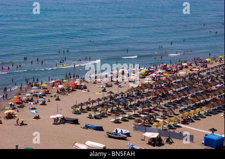 Maître-nageur SUR LA PLAGE DE FUENGIROLA COSTA DEL SOL entouré par les vacanciers sous parasols colorés Banque D'Images