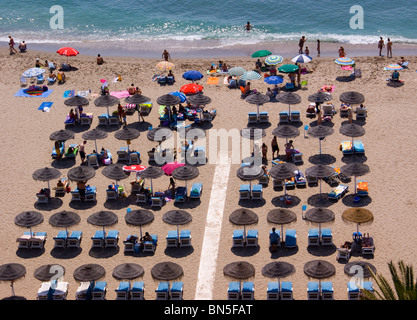 Maître-nageur SUR LA PLAGE DE FUENGIROLA COSTA DEL SOL entouré par les vacanciers sous parasols colorés Banque D'Images