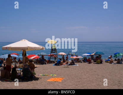 Maître-nageur SUR LA PLAGE DE FUENGIROLA COSTA DEL SOL entouré par les vacanciers sous parasols colorés Banque D'Images