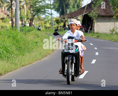 Deux jeunes garçons balinais équitation une moto et vêtus de vêtements du temple. Près de Ubud, Bali, Indonésie Banque D'Images